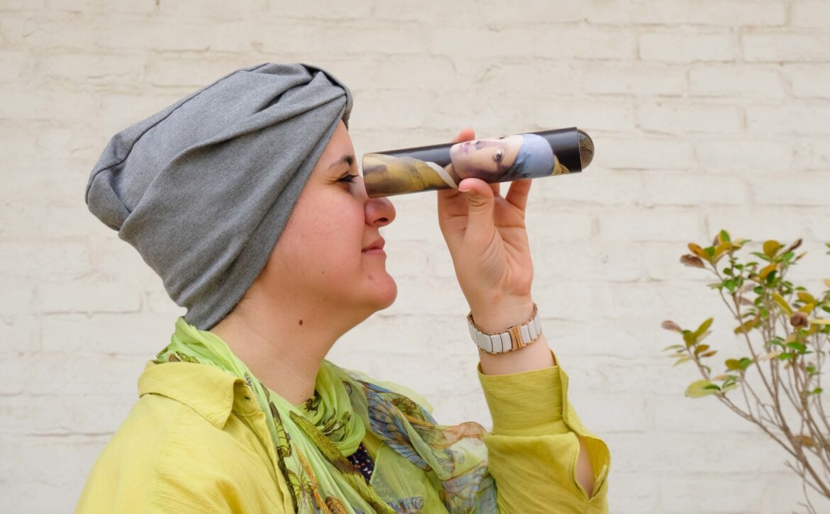 Woman looking through a rolled up piece of paper