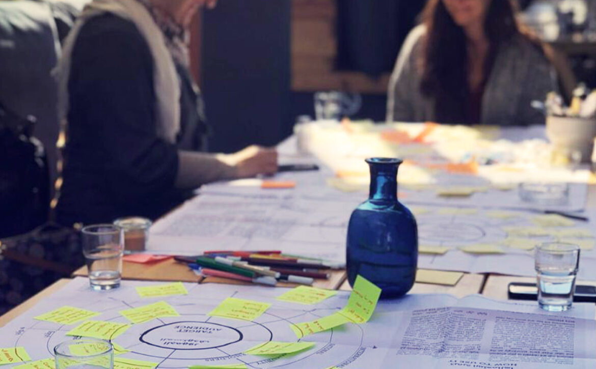 Two women smiling and working in the background, and a post-it note activity in the foreground.